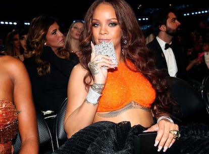 No sabemos si lo que lleva la cantante en la mano es un teléfono móvil muy emperifollado o una petaquita igual de recargada. Pero Rihanna no parece tener intención de soltarlo ni aunque le toque subir a coger un Grammy.
