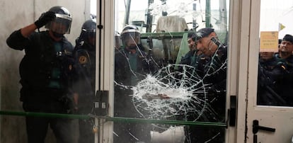 Oficiales de la Guardia Civil rompen una puerta de cristal en un punto de votación del referéndum ilegal de independencia.