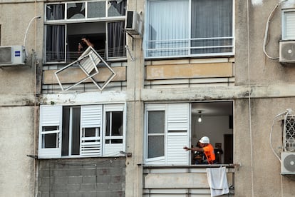 An Israeli emergency service official on Monday next to a window damaged by a Hamas attack in Ashkelon. 