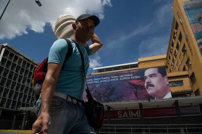 Un hombre con cubrebocas camina frente a una imagen de Nicolás Maduro en el centro de Caracas, el 6 de julio.