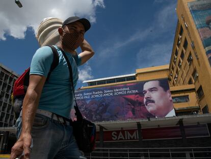 Un hombre con cubrebocas camina frente a una imagen de Nicolás Maduro en el centro de Caracas, el 6 de julio.