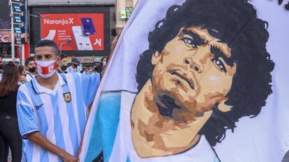 Un aficionado argentino sujeta una pancarta con el rostro de Diego Armando Maradona, que falleció ayer y sumió a la nación en el luto.