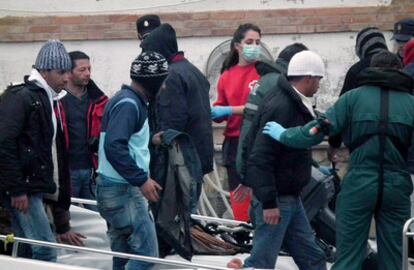 Varios de los 23 inmigrantes argelinos interceptados esta mañana frente a las costas de Cartagena a bordo de dos pateras, a su llegada al puerto de la ciudad en una patrullera de la Guardia Civil.