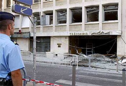 Un policía contempla los daños causados por una bomba en el edificio de la Tesorería y Aduanas de Niza.