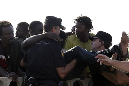 Police grappling with immigrants on Ceuta's beach after a mass attempt to swim onto Spanish soil.