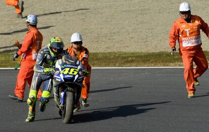 El piloto de Movistar Yamaha, Valentino Rossi, es ayudado por los comisarios de pista después de su caída en el circuito de Motegi.