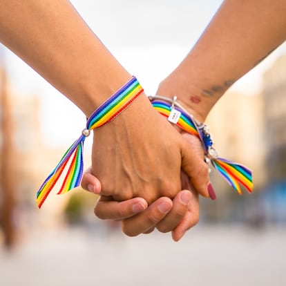Hands of lesbian women with a ribbon of LGBT rainbow colors tied together; LGBT pride concept, LGBTQ people, lgbt rights campaign, same sex marriage