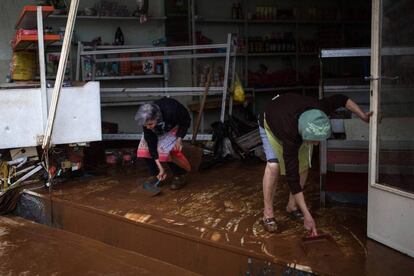 Desde primeras horas de la mañana, las tareas de rescate y limpieza están siendo dificultadas por un nuevo frente de lluvias en toda Grecia. En la imagen, dos mujeres limpian de barro en interior de una tienda en Mandra, el 15 de noviembre de 2017.
