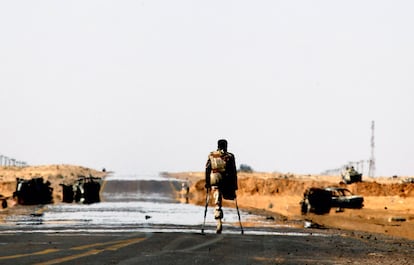 Un soldado rebelde, con la pierna amputada, camina por el frente al oesta de Ajdabiya, entre vehículos calcinados.