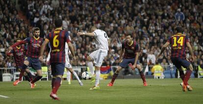 Benzema remata a portería ante Piqué y Busquets