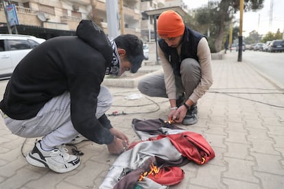 Dos jóvenes queman la bandera del régimen de El Asad, en las calles de Qamishli (Siria).