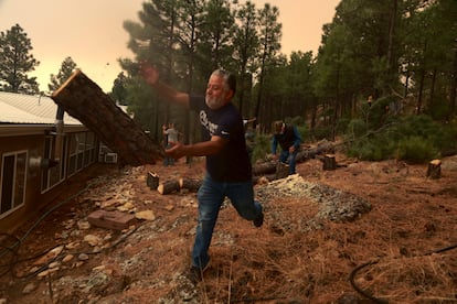 Chris Castillo arroja un tronco recién cortado. Él y sus primos hacen un cortafuegos junto a la casa de un familiar en Las Vegas, Nuevo México (EE UU), el lunes. Las llamas, avivadas por el viento, siguen avanzando por las laderas de las montañas secas de Nuevo México, lo que obliga a la evacuación de los residentes del área y a decenas de pacientes del hospital psiquiátrico del Estado, mientras los bomberos se esfuerzan por evitar nuevos incendios forestales.