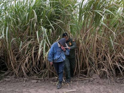 Un agente de la frontera detiene a migrantes escondidos que intentan entrar en EE UU.