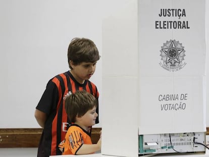 Crianças olham para urna eletrônica durante sessão em colégio eleitoral de São Paulo.