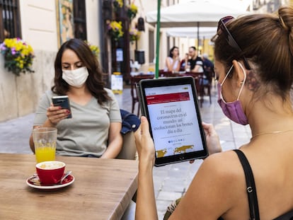 Una lectora consulta EL PAÍS en su tableta en una terraza de Valencia.