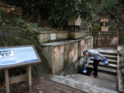 Un vecino recoge agua de  la fuente de agua potable Font Vella en Sant Hilari Sacalm (Girona).