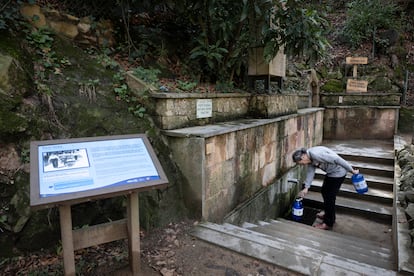 Un vecino recoge agua de  la fuente de agua potable Font Vella en Sant Hilari Sacalm (Girona).