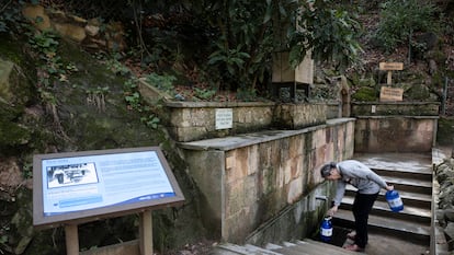 Un vecino recoge agua de  la fuente de agua potable Font Vella en Sant Hilari Sacalm (Girona).