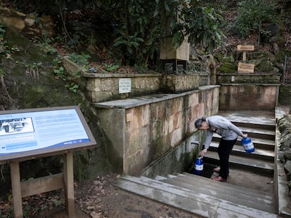 Un vecino recoge agua de  la fuente de agua potable Font Vella en Sant Hilari Sacalm (Girona).