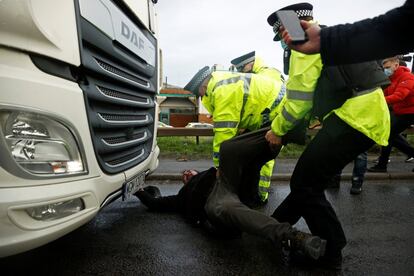 Agentes de policía arrastran a un camionero tumbado frente a un vehículo en el puerto de Dover, mientras los países de la UE imponen una prohibición de viajar desde el Reino Unido tras el brote de la enfermedad por coronavirus.