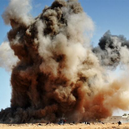 Varios rebeldes corren a ponerse a cubierto de una bomba lanzada por las fuerzas de Gadafi.