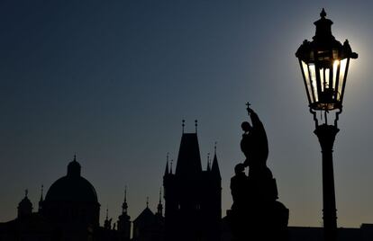 Siluetas de edificios y estatuas del puente Carlos de Praga, en la  Rep&uacute;blica Checa, fotografiados al amanecer. 