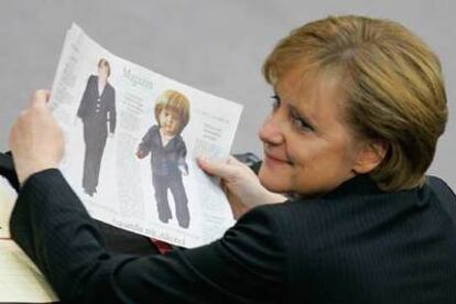 Angela Merkel sostiene un periódico en el que se muestra a una muñeca inspirada en la futura canciller.