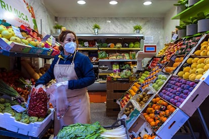 Una vendedora de frutas sirve a una clienta.