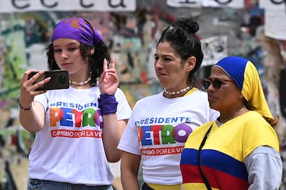 Tres mujeres en los alrededores de la Plaza Bolívar se reúnen para presenciar los actos por la ceremonia de investidura de Gustavo Petro como presidente de Colombia.
