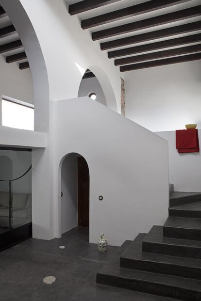 En el antiguo pajar destacan la gran arquería, las puertas correderas metálicas (a la izquierda) y la escalera que conecta con la entreplanta y que está inspirada en los diseños de Ricardo Bofill.