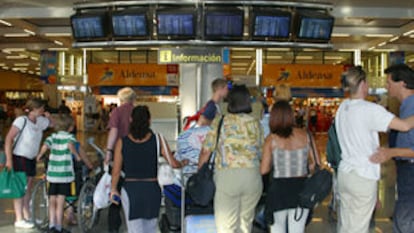Varias personas observan el panel de horarios del aeropuerto de Mallorca, que sufrió graves retrasos.