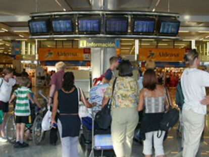 Varias personas observan el panel de horarios del aeropuerto de Mallorca, que sufrió graves retrasos.