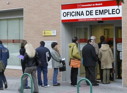 Un grupo de personas hacen cola ante una oficina de empleo.