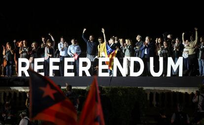 Manifestantes pro-independentistas saludan desde detrás de la palabra 'Referèndum' en Barcelona.