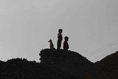 Dos niños con su perro sobre un escarpado promontorio de Cerro Rico al atardecer.