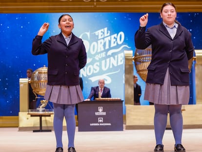 MADRID, 22/12/2024.- Las niñas de la Residencia San Ildefonso de Madrid Yadira Quinde Mendoza (i) y Kiara Román Benítez (d) muestran el número 45.225, uno de los quintos premios, durante el sorteo de la Lotería de Navidad que se celebra este domingo en el Teatro Real, en Madrid. EFE/Javier Lizón