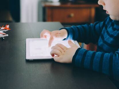 Un niño mira con atención su tableta. 
 