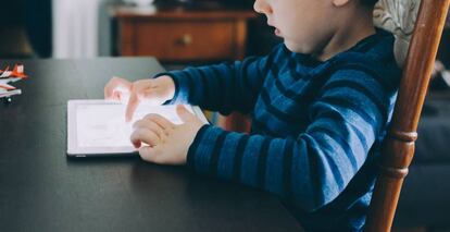 Un niño mira con atención su tableta. 
 