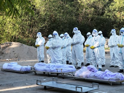 Un grupo de voluntarios reza ante los cuerpos de víctimas de la covid durante un funeral en la ciudad birmana de Mandalay el 14 de julio