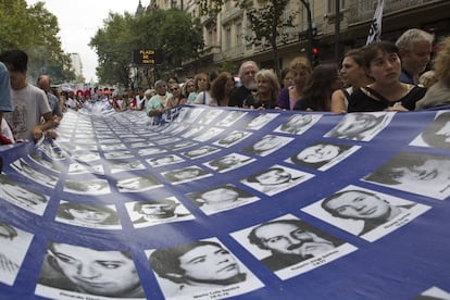 Una multitud lleva la pancarta con los nombres y rostros de los desaparecidos en la dictadura.