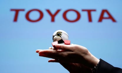 Una empleada de Toyota sostienen un Kirobo Mini durante la presentación. El robot incluye una "cuna" que se dobla como si fuera un asiento de bebé diseñado para encajar en los portavasos coche.