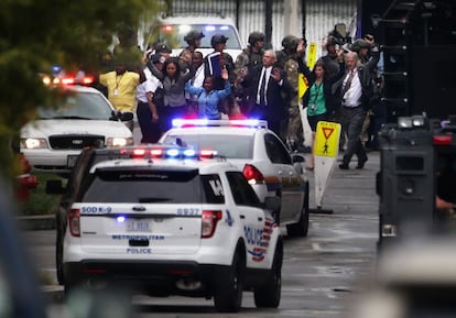 Un grupo de gente abandona un edificio con los brazos en alto tras el tiroteo que ha tenido lugar en el mando de la Armada en Washington.