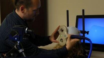 Un investigador coloca el aparato de estimulación transcraneal a una de las participantes en el experimento.