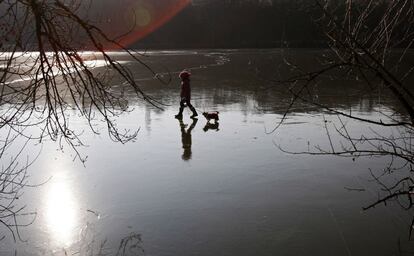 Una niña camina con su perro por un lago helado en Praga, República Checa.