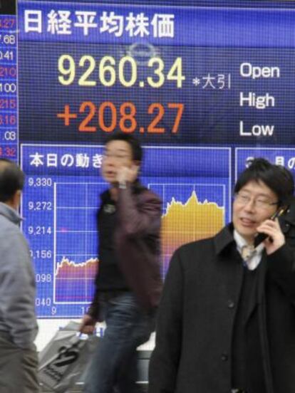 Ejecutivos caminan frente a un tablero electrónico en la Bolsa de Tokio.