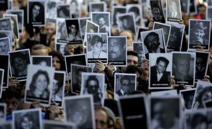 Ciudadanos sostienen fotografías de personas que murieron en el centro judío AMIA, en el que conmemoran 22 aniversario.