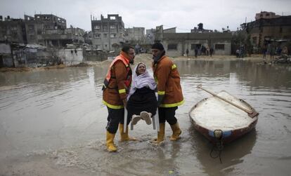 Dos miembros de los equipos de rescate palestinos evacúan a una mujer de una casa inundada tras una fuerte tormenta en el campo de refugiados de Jabaliya (Franja de Gaza).