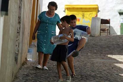 Una vecina y dos niños de Almodóvar del Río cargan botellas de agua mineral.