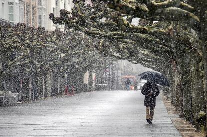 Una persona camina mientras nieva por la calle de Burgos , este jueves.