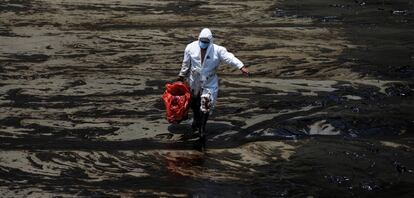 Un trabajador camina en la playa peruana de Ventanilla tras un derrame de petróleo causado por olas anormales, provocadas por la erupción del volcán Hunga Tonga-Hunga Ha'apai.